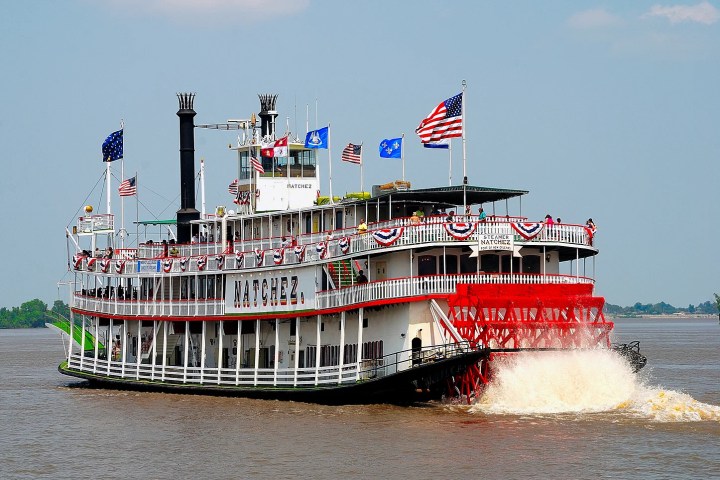 a large ship in a body of water with Delta Queen in the background